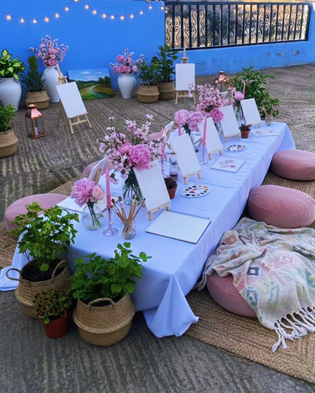 Table d'atelier créatif fleurie avec chevalets, toiles blanches et peintures à Tayri Aura