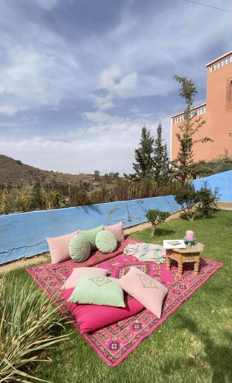 Coin détente avec coussins roses et verts sur la pelouse