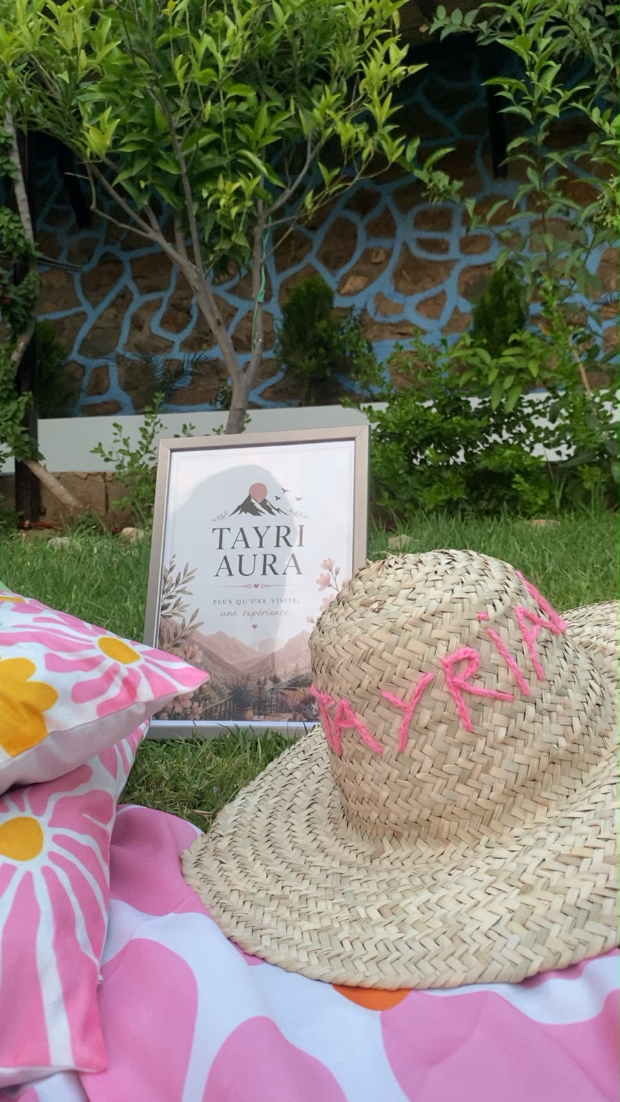 Cadre Tayri Aura et chapeau en paille brodé posés dans le jardin